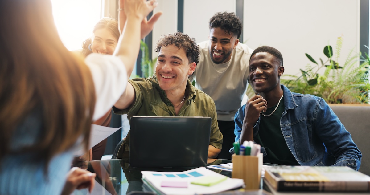Two people high fiving in a group meeting